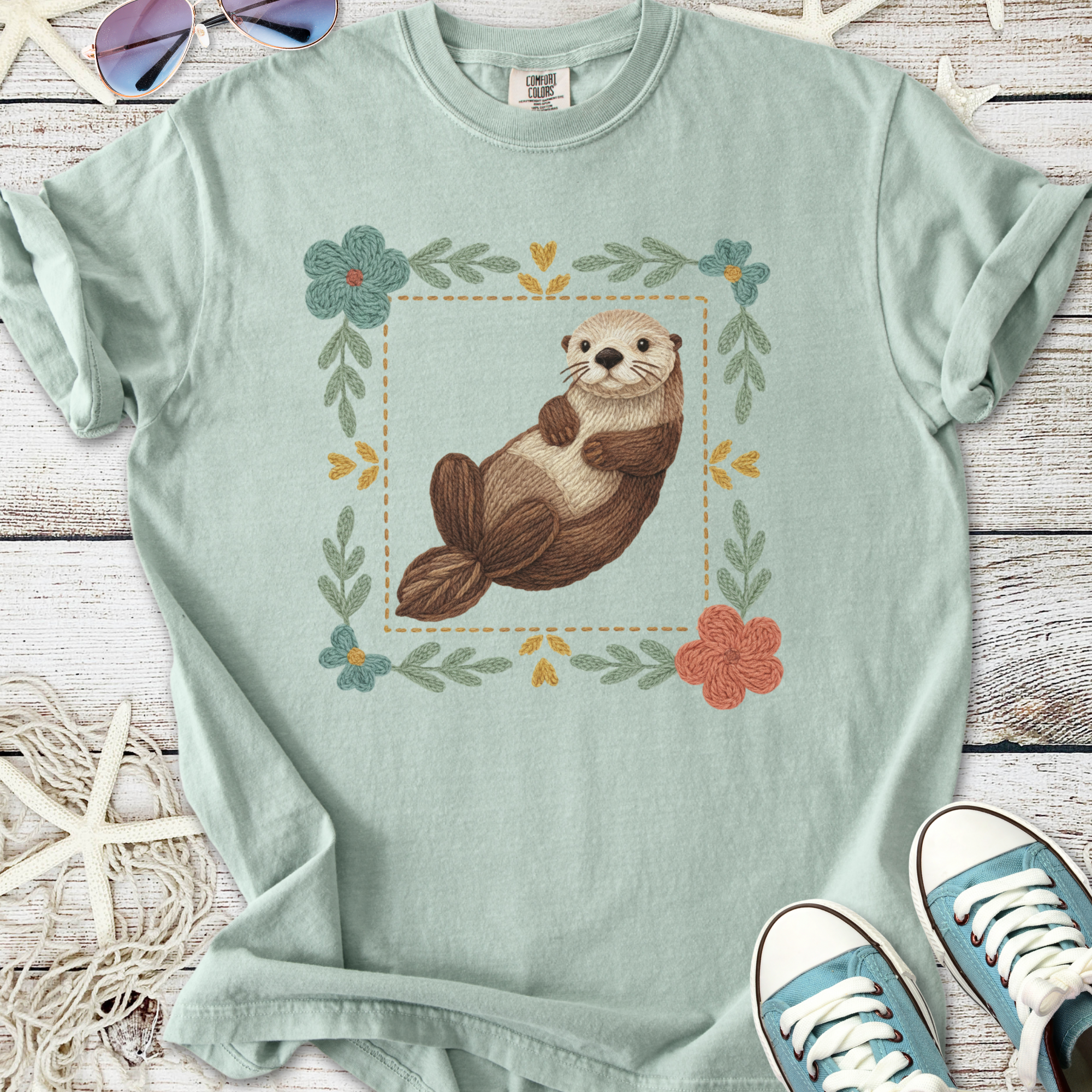 Mint green t-shirt featuring a cute otter graphic with floral design, made of soft cotton fabric.