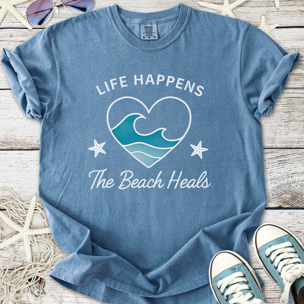 Blue beach-themed t-shirt with 'Life Happens, The Beach Heals' graphic, made of soft cotton.