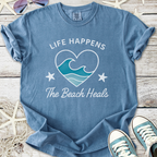 Blue beach-themed t-shirt with 'Life Happens, The Beach Heals' graphic, made of soft cotton.