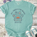 Teal graphic t-shirt with beach-themed paw print design saying 'All I Need Is The Beach And My Dog'