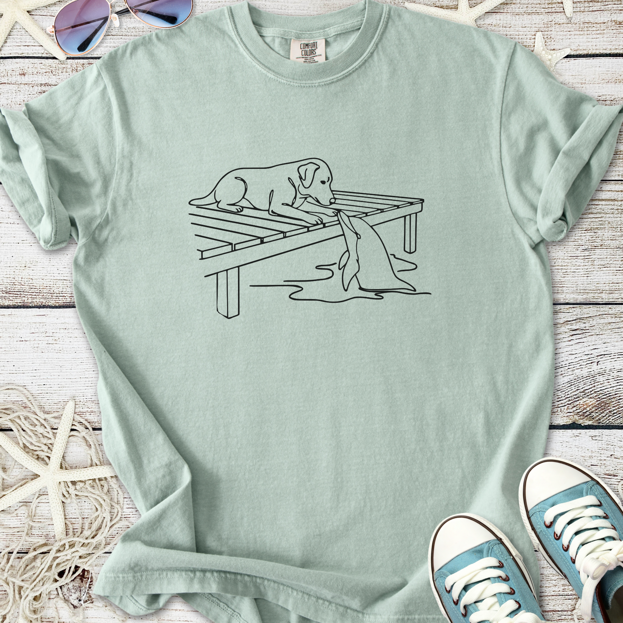 Mint green dog graphic tee featuring a playful dog on a dock with a fish, made from soft cotton.