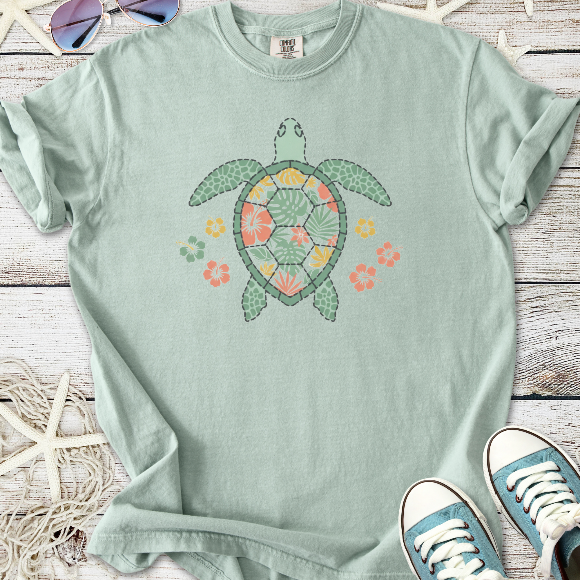 Light green t-shirt featuring a colorful turtle design with floral accents, perfect for beachwear.