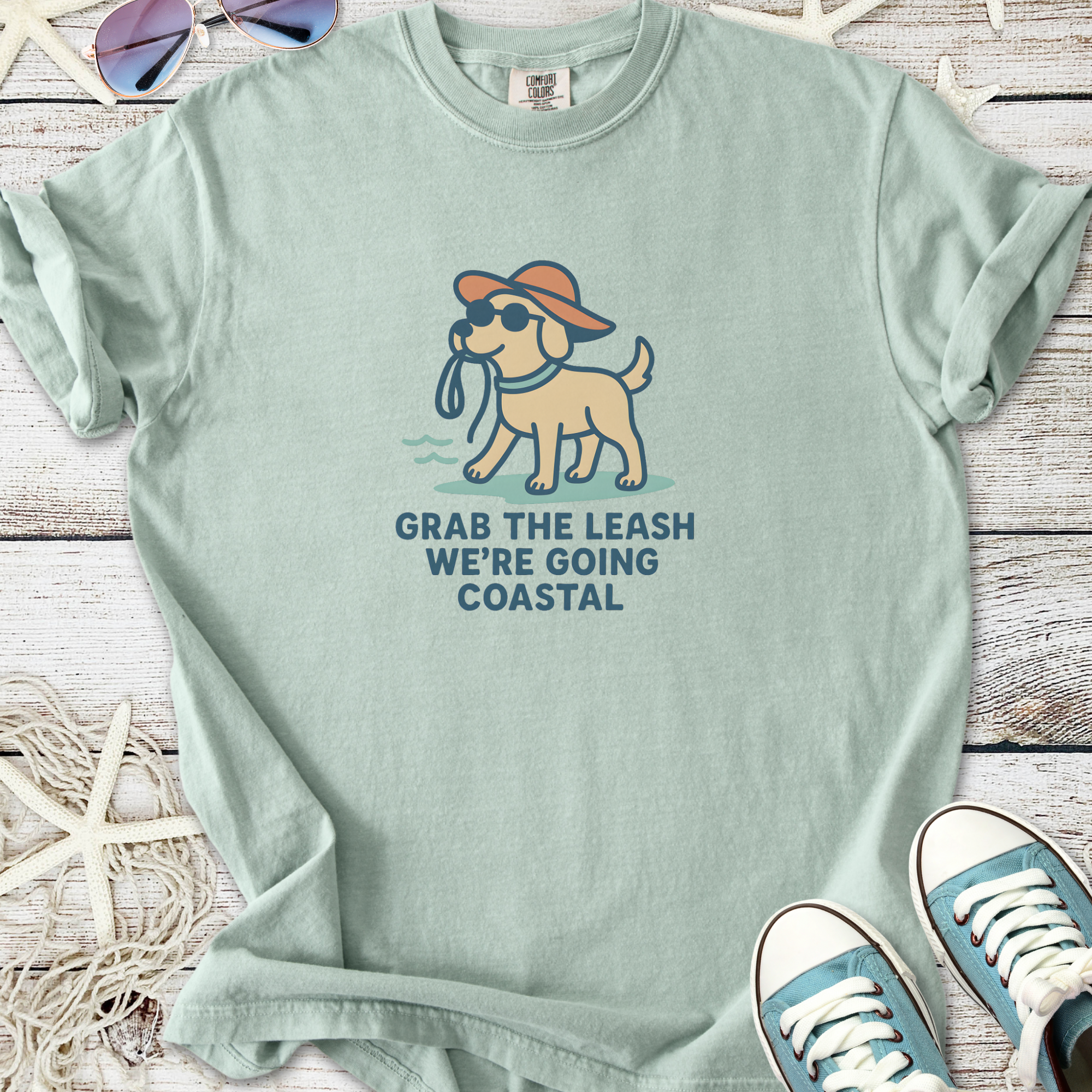 Mint green t-shirt featuring a playful dog graphic and the phrase 'Grab the leash, we’re going coastal'.