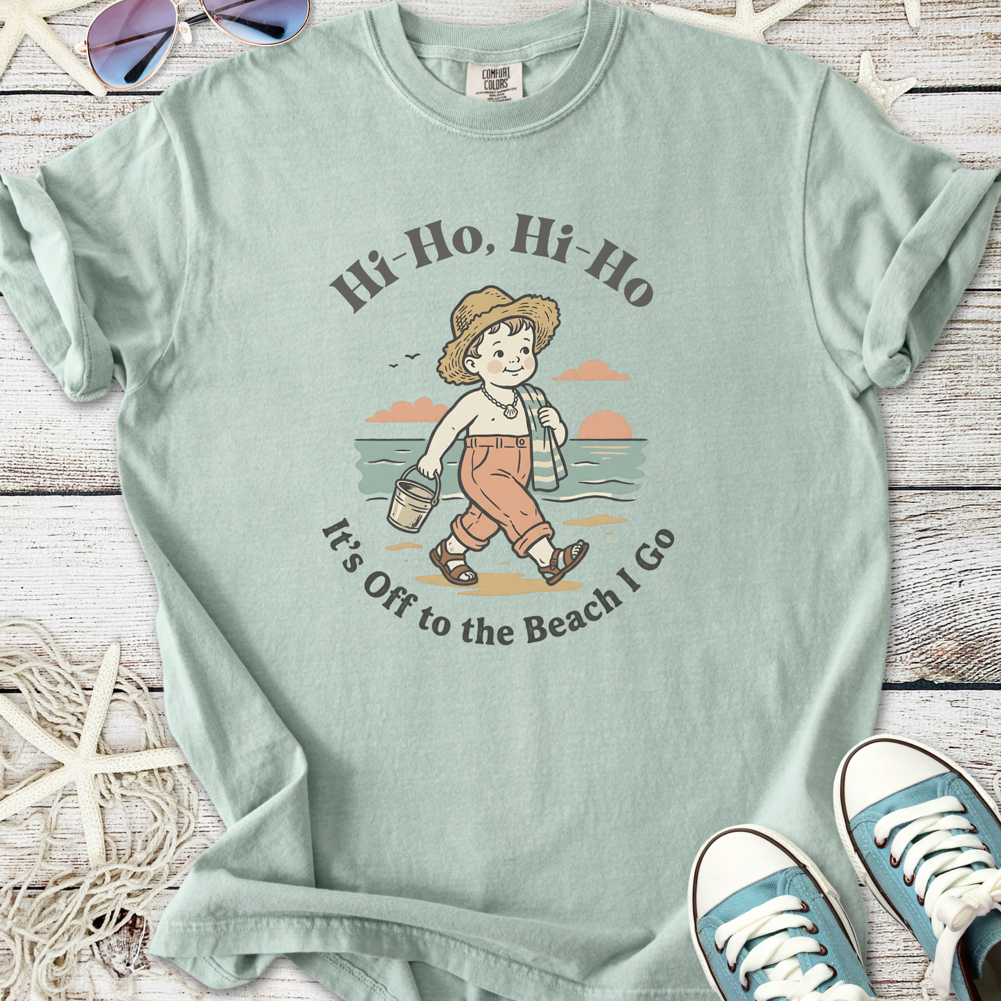 Mint green t-shirt featuring playful beach graphic with child and text 'Hi-Ho, Hi-Ho, It's Off to the Beach I Go'