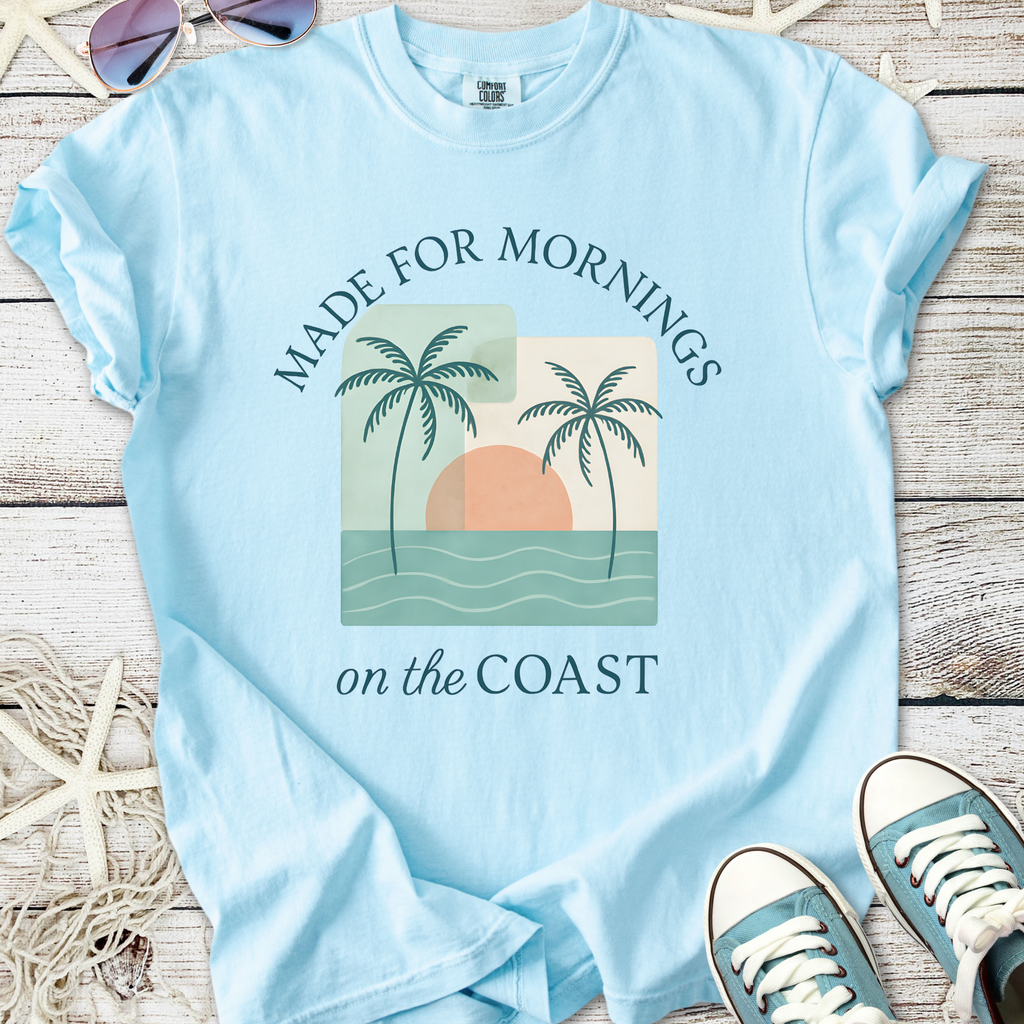 Light blue t-shirt with beach-themed print, featuring palm trees and sunset. Perfect for coastal mornings.