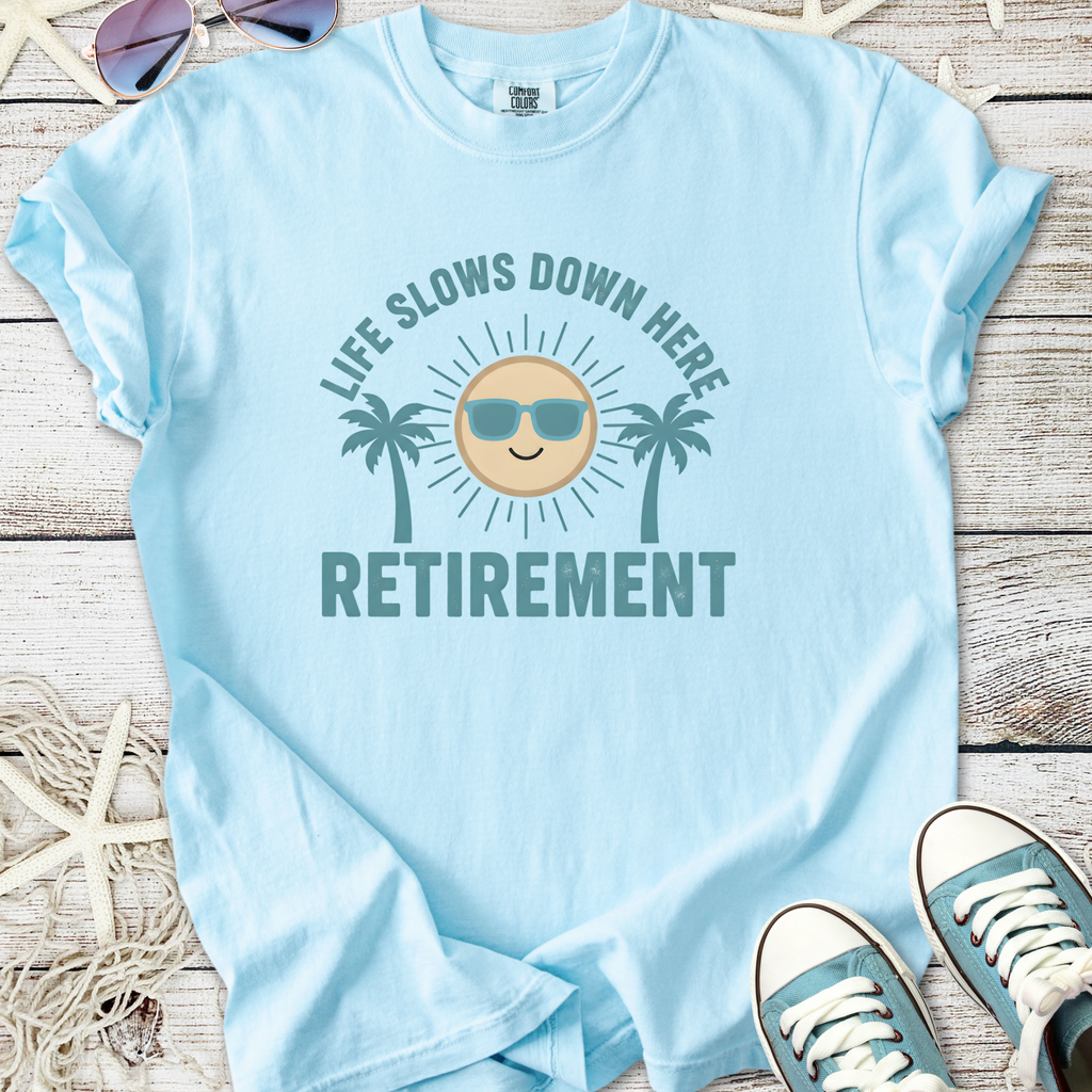 Light blue cotton t-shirt with 'Life Slows Down Here Retirement' graphic and palm trees design.