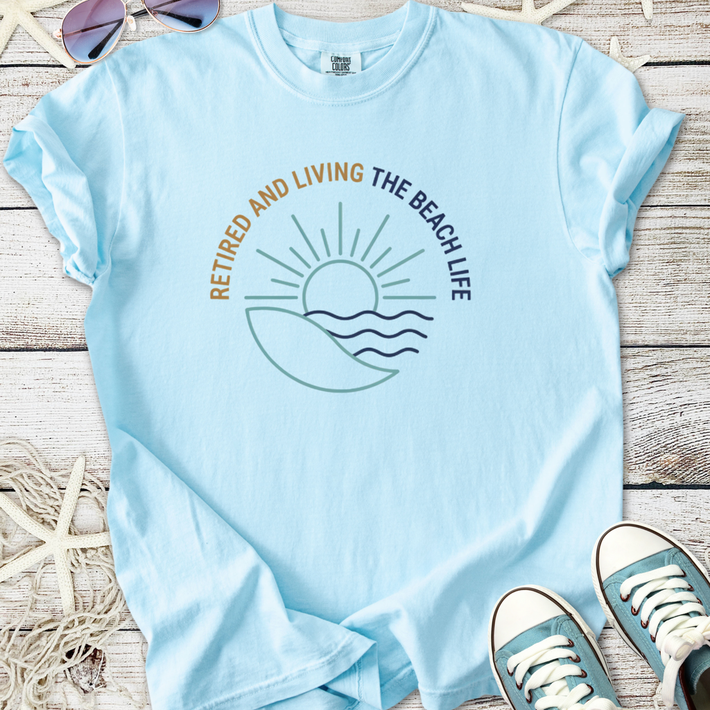 Light blue t-shirt with 'Retired and Living the Beach Life' graphic, perfect for beach lovers.