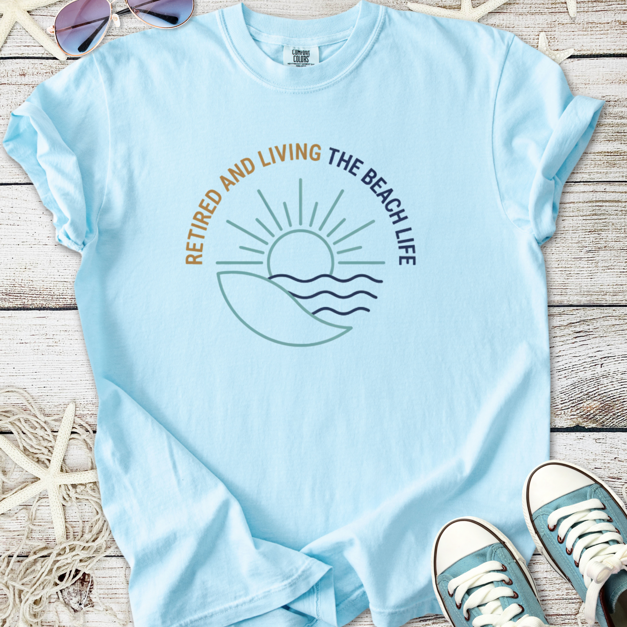 Light blue t-shirt with 'Retired and Living the Beach Life' graphic, perfect for beach lovers.