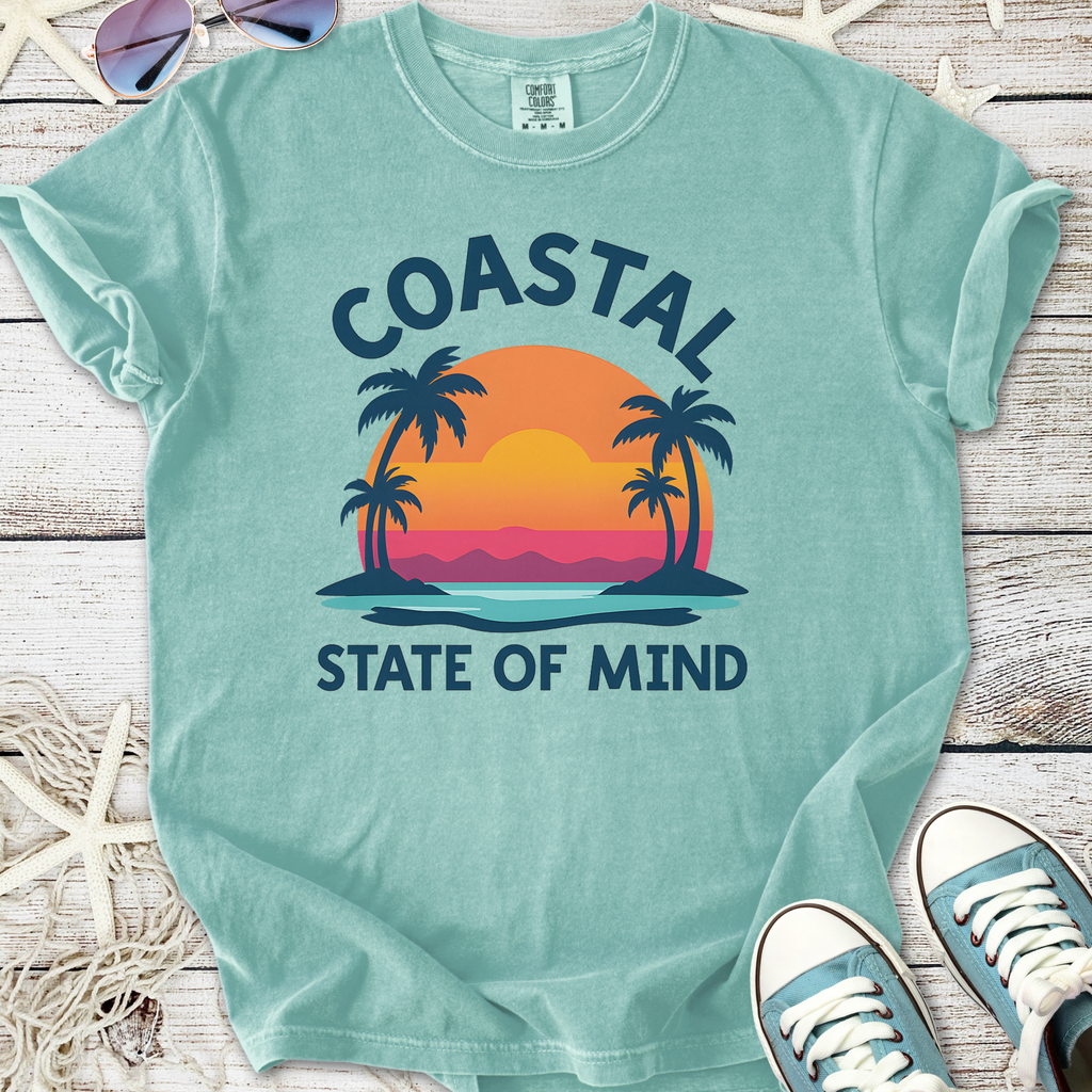 Mint green t-shirt featuring 'Coastal State of Mind' graphic with sunset and palm trees, made from soft cotton.
