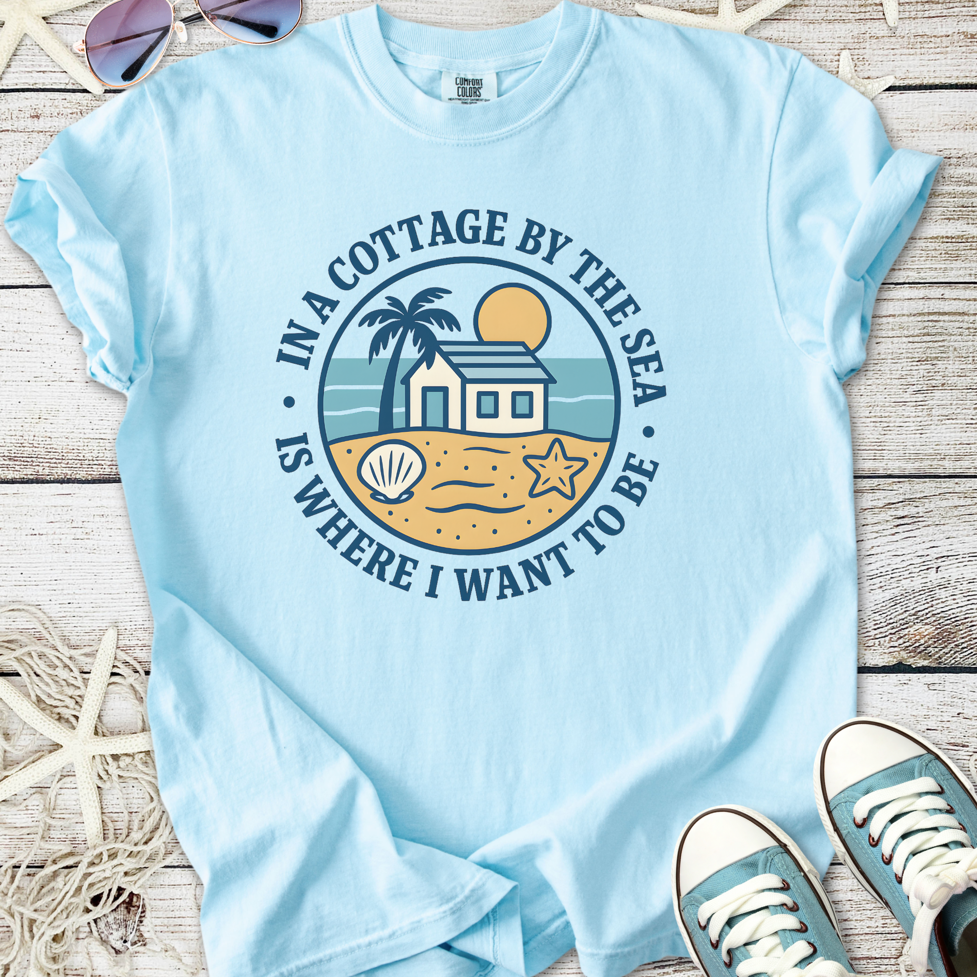 Light blue cotton t-shirt with beach cottage graphic, palm trees, and seashell design.