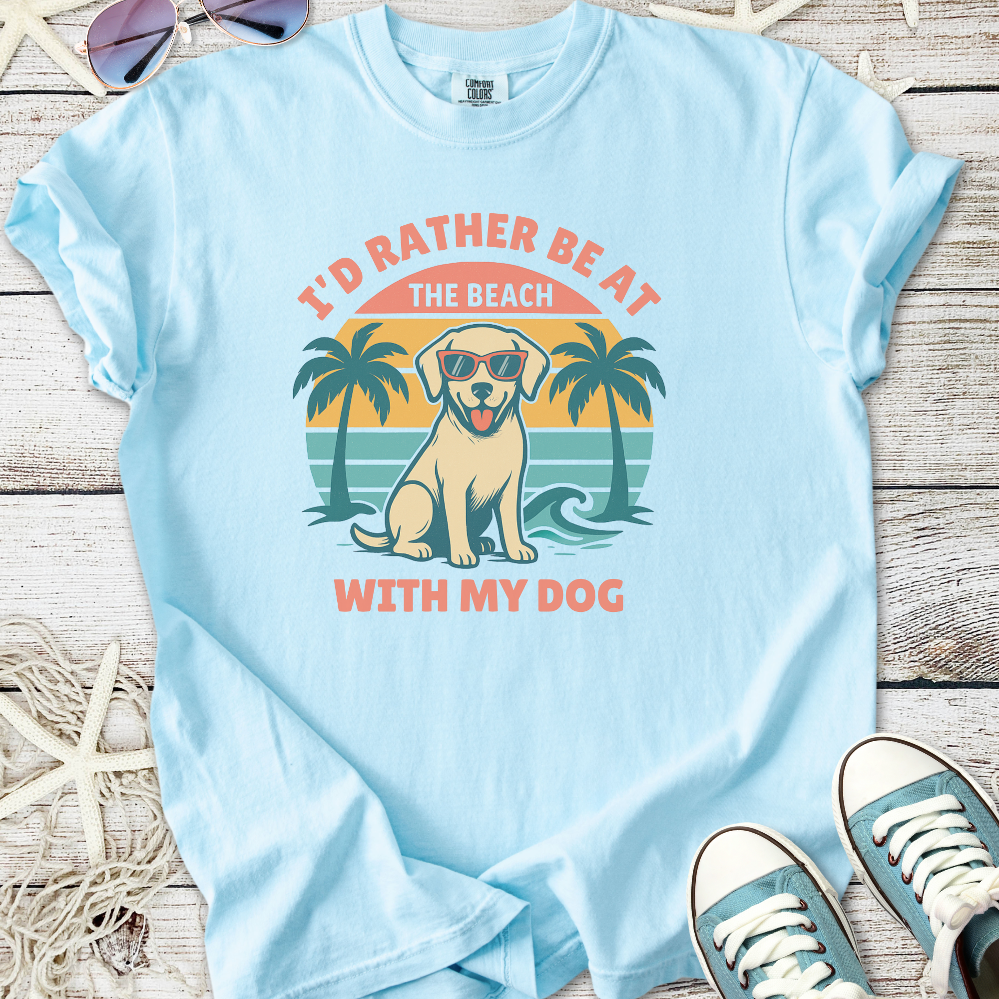 Light blue t-shirt featuring a dog with sunglasses and palm trees, perfect for dog lovers.
