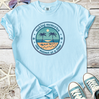 Light blue t-shirt with sunset graphic, palms, and text 'making memories one sunset at a time', casual style.