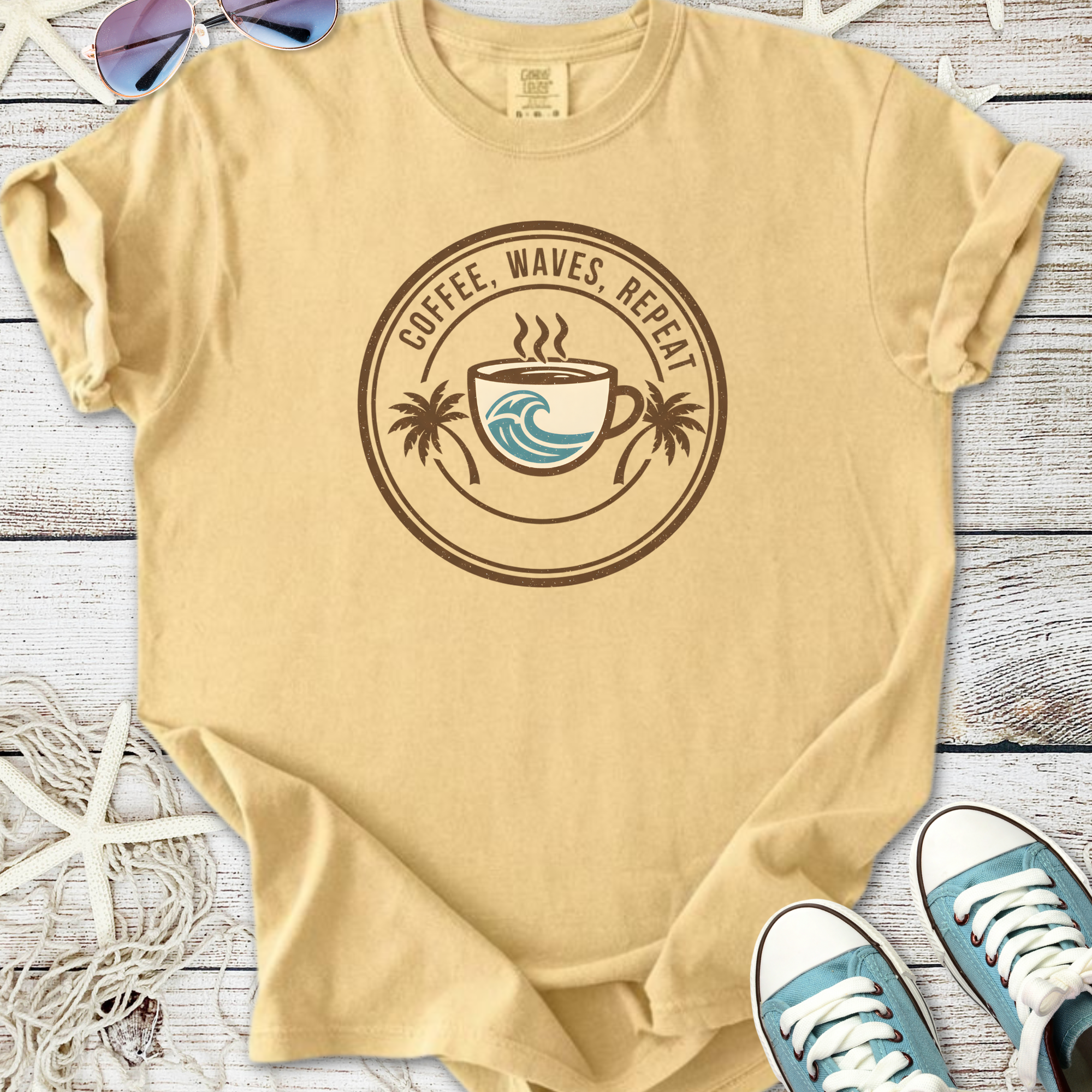Beige cotton t-shirt with 'Coffee, Waves, Repeat' graphic and palm tree design. Perfect for casual beachwear.
