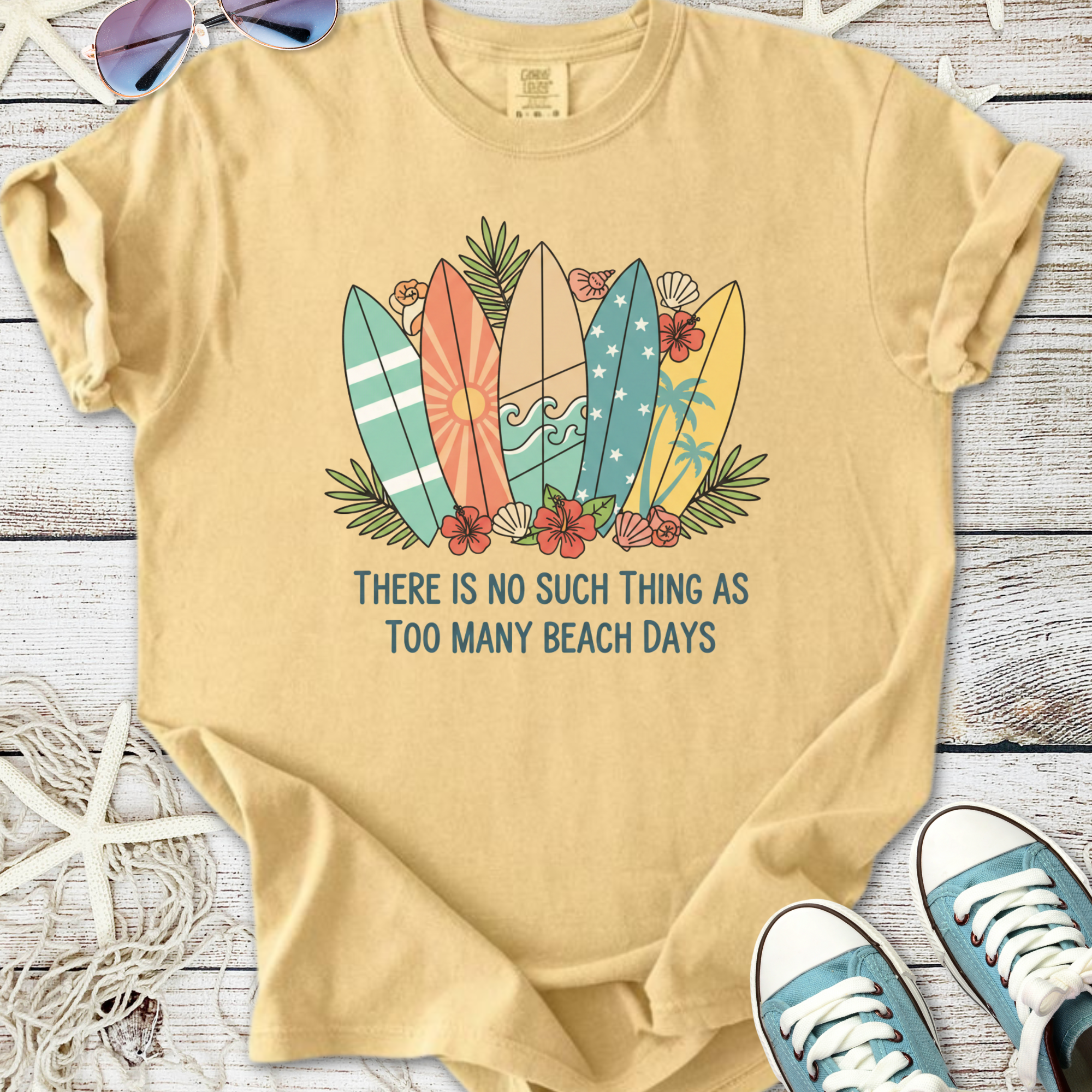 Light beige t-shirt with colorful surfboards design and 'Too Many Beach Days' text, perfect for summer.