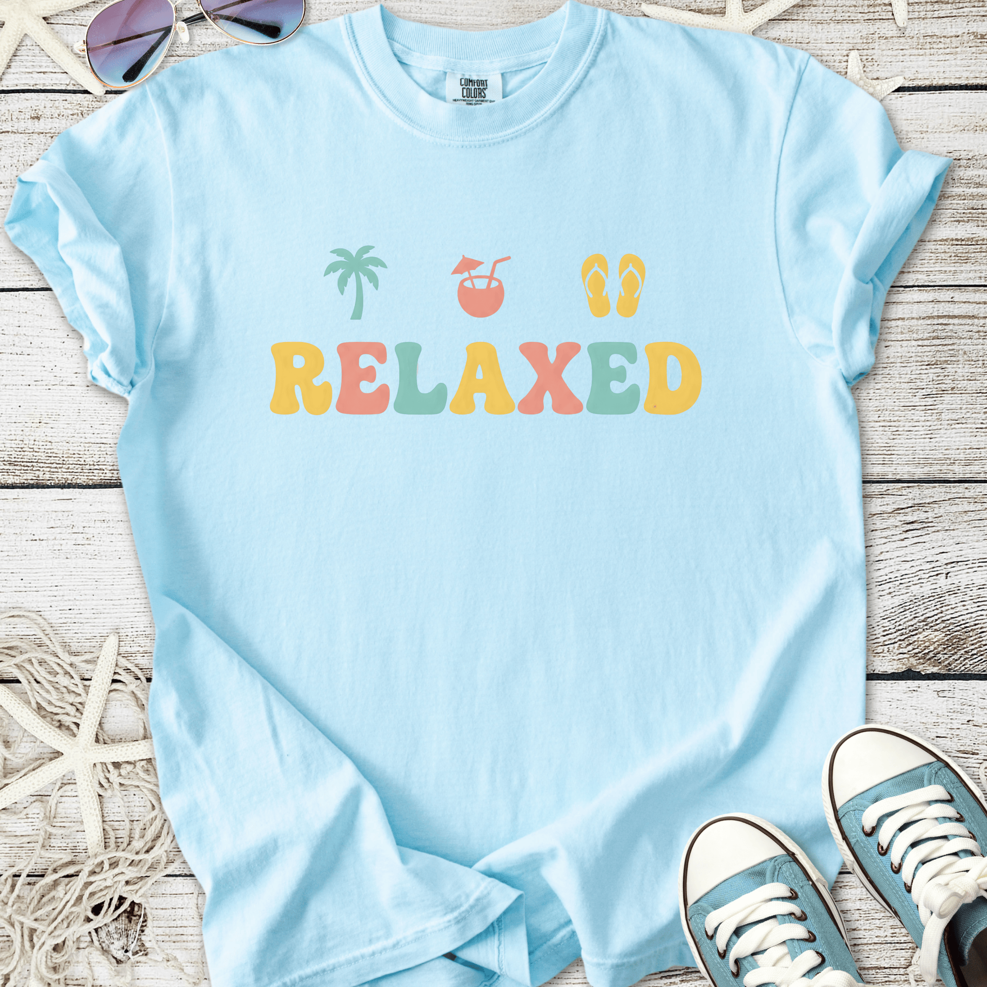 Light blue relaxed fit t-shirt with colorful beach-themed design and soft cotton material.