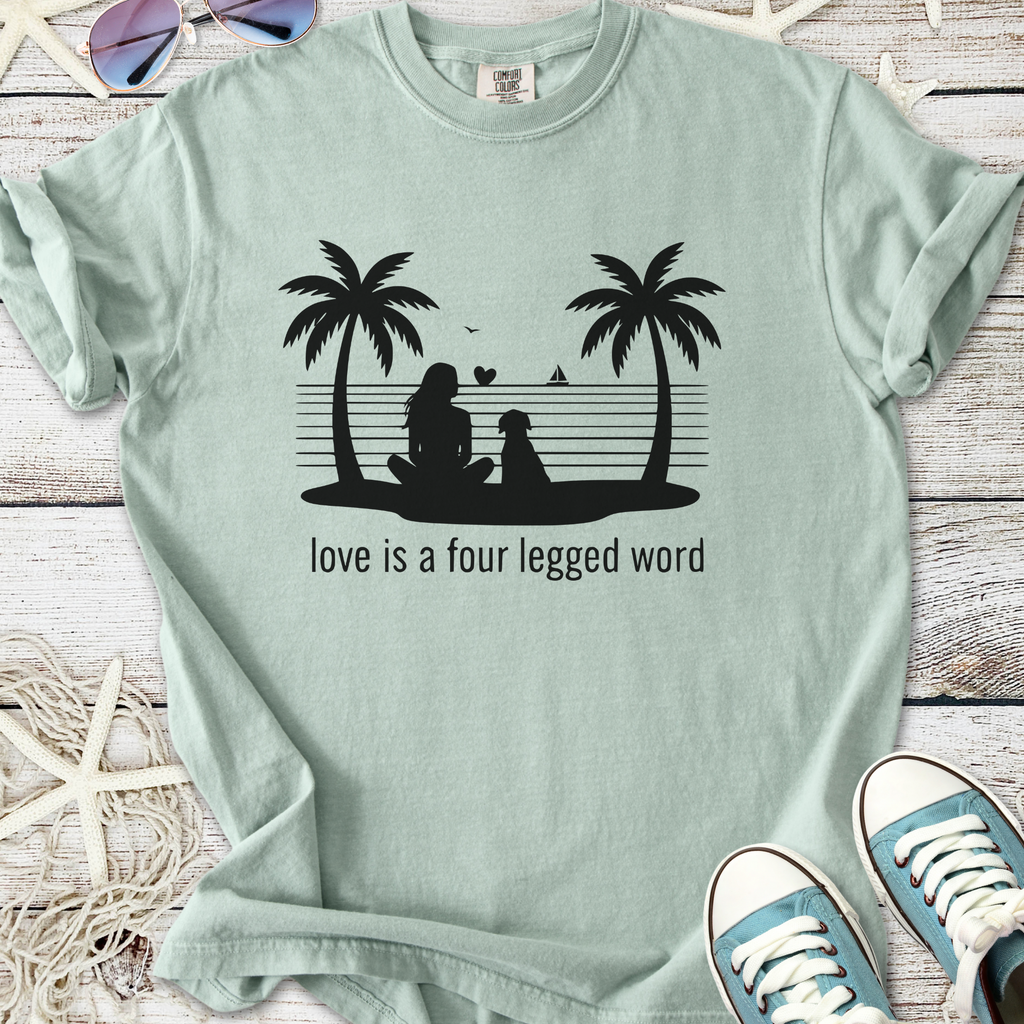 Mint green t-shirt with printed design of a woman and dog under palm trees with slogan about love.