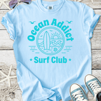 Light blue Ocean Addict Surf Club t-shirt featuring surfboard and sun graphic, perfect for beach lovers.