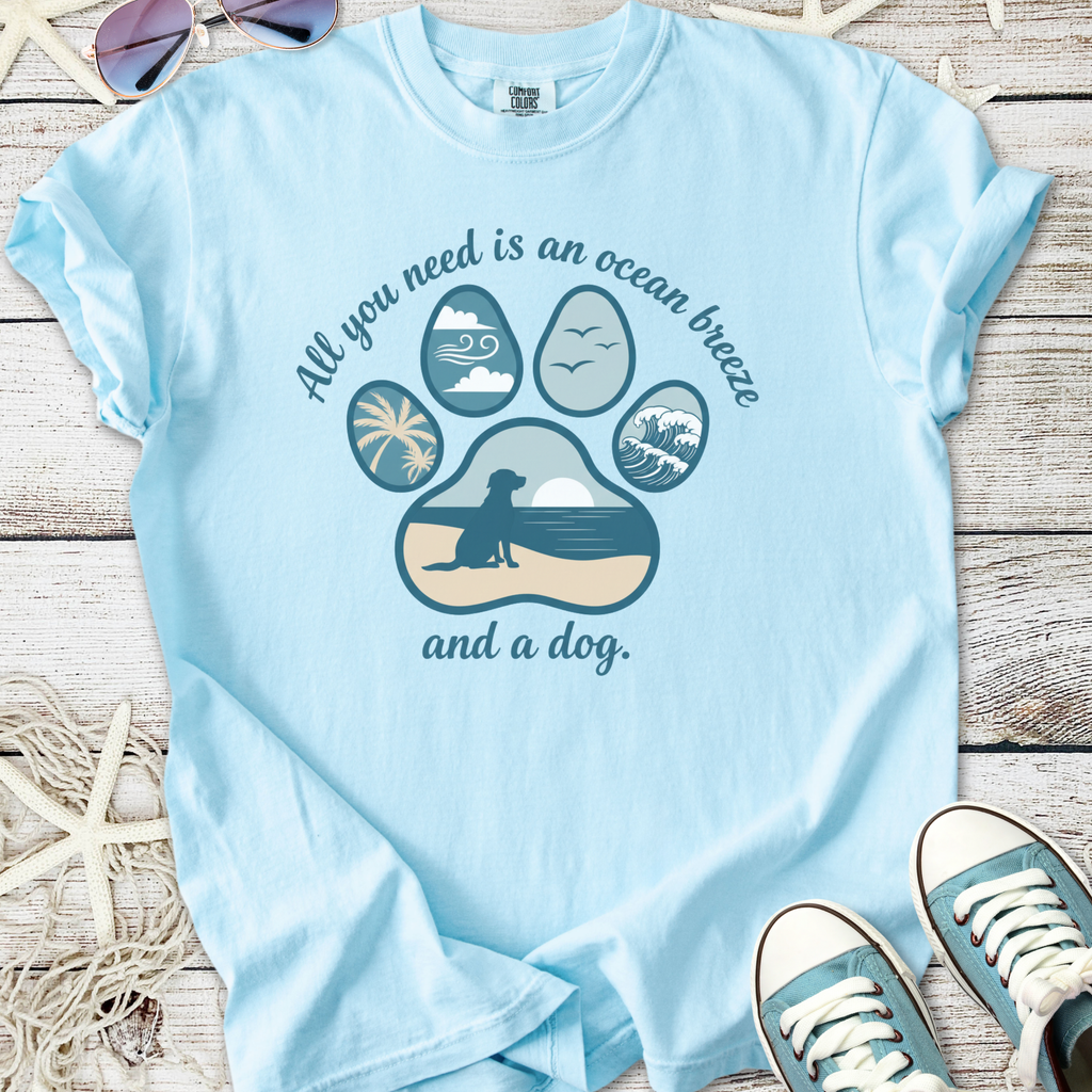 Light blue graphic t-shirt featuring a paw print design with ocean and dog theme.