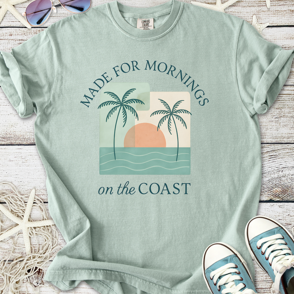 Light seafoam green t-shirt with palm tree graphic and 'Made for Mornings on the Coast' text.