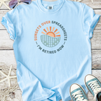 Light blue t-shirt with 'Sunsets Over Spreadsheets I'm Retired Now' graphic design.