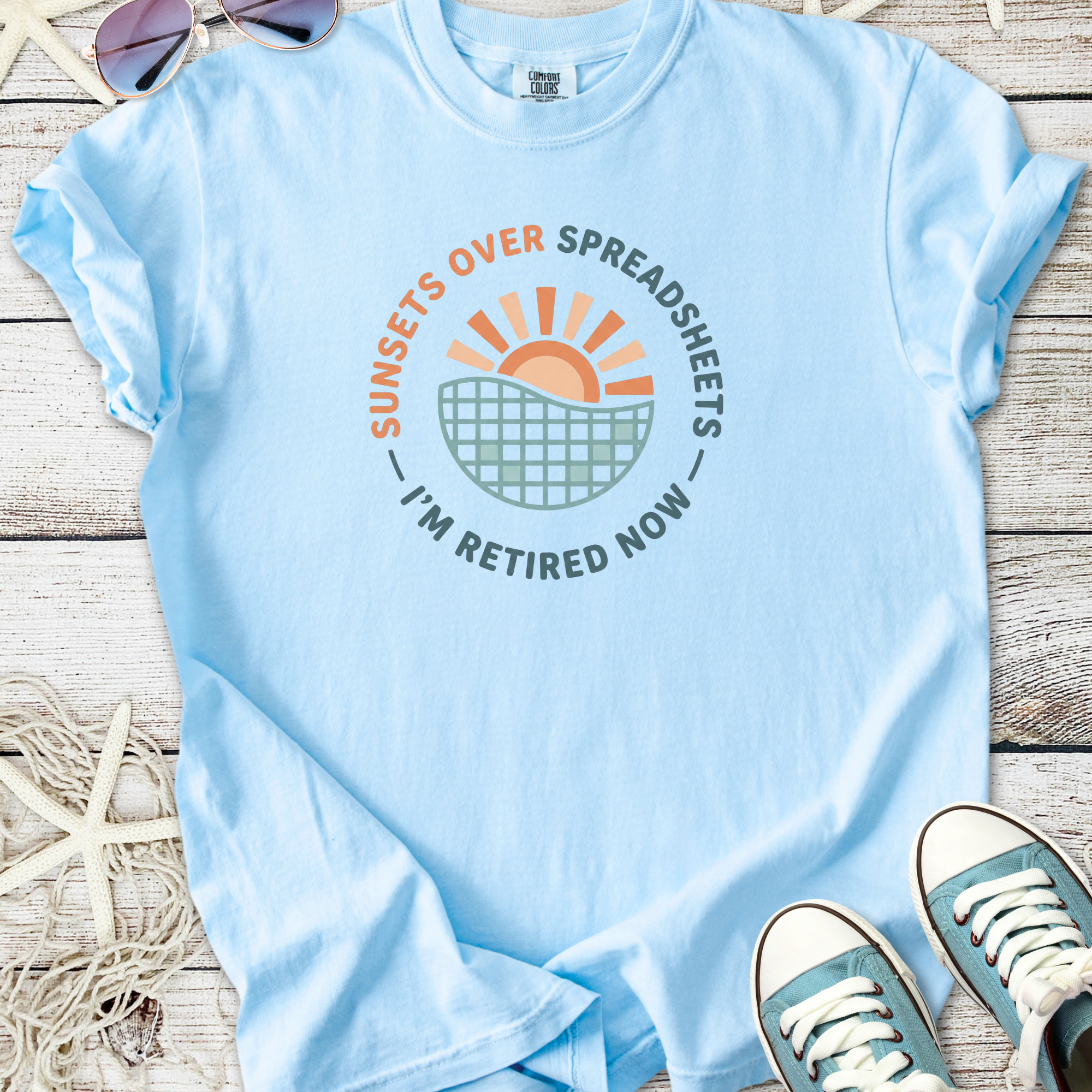 Light blue t-shirt with 'Sunsets Over Spreadsheets I'm Retired Now' graphic design.