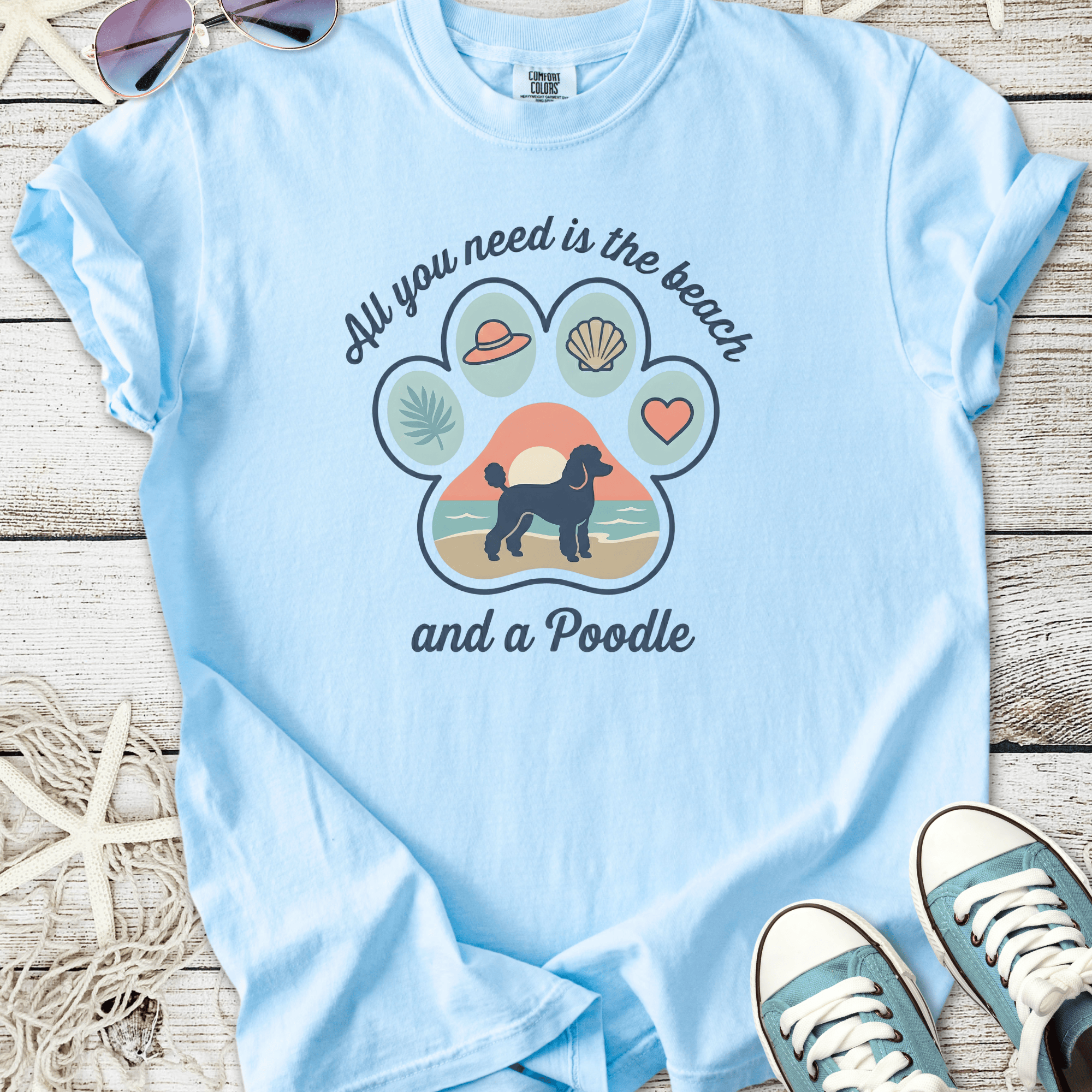 Light blue t-shirt featuring a playful poodle graphic and beach theme, perfect for dog lovers.