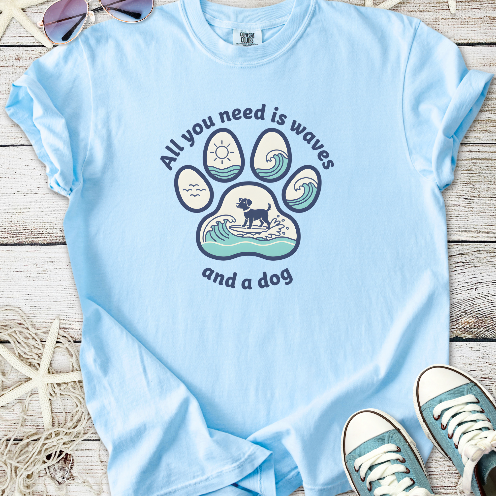 Light blue graphic t-shirt featuring a dog paw design with waves and sun, perfect for dog lovers.