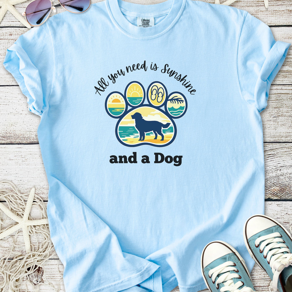 Light blue t-shirt with dog paw graphic and 'All you need is sunshine and a Dog' text, made of soft cotton.