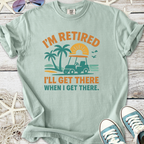 Light teal retired graphic tee with palm trees and golf cart, featuring the text 'I'm Retired, I'll Get There.'