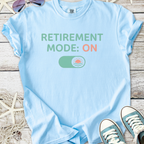 Light blue t-shirt with 'Retirement Mode: ON' graphic, perfect for relaxed retirement fashion.
