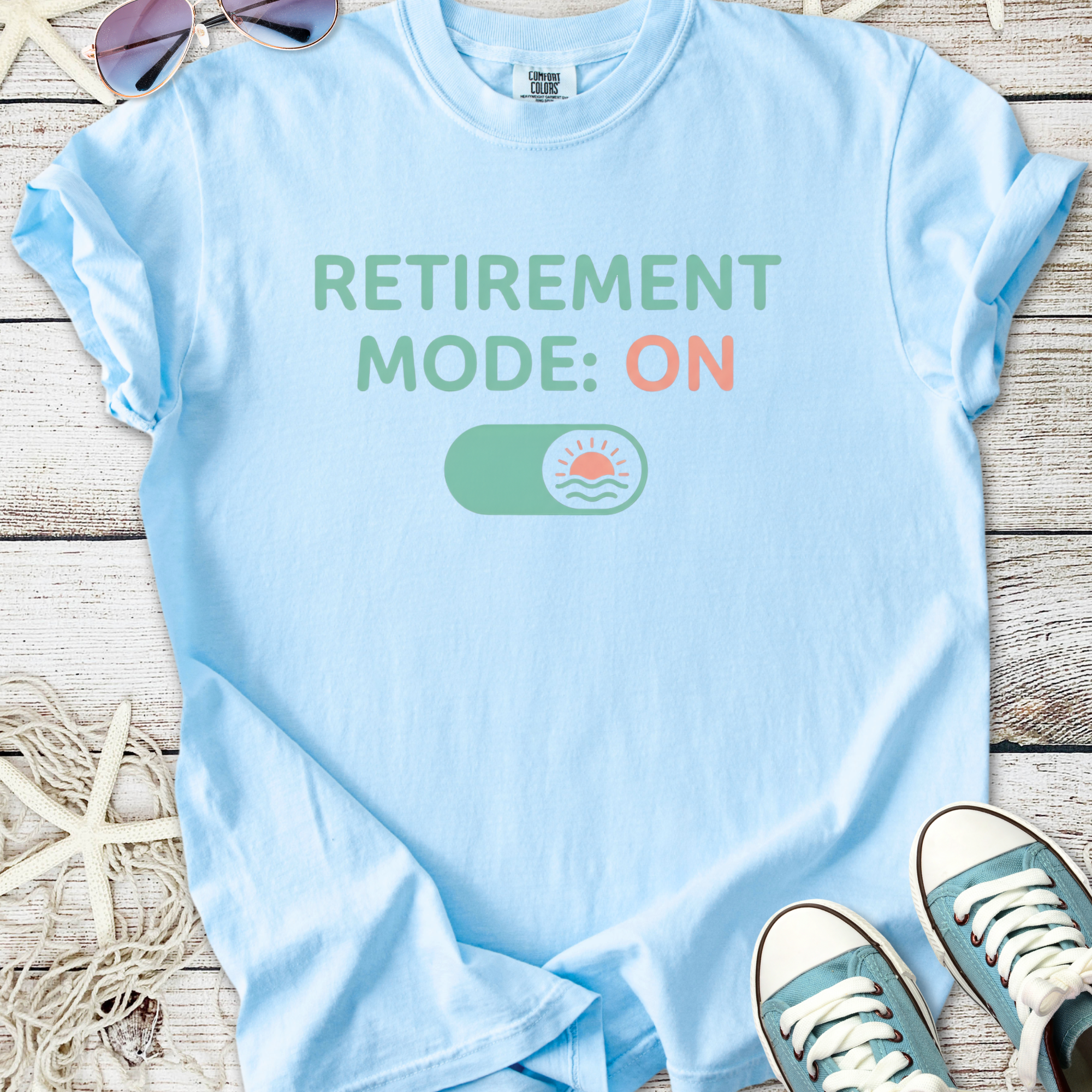 Light blue t-shirt with 'Retirement Mode: ON' graphic, perfect for relaxed retirement fashion.