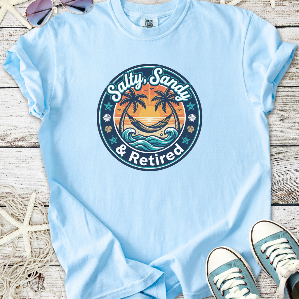Light blue t-shirt with 'Salty, Sandy & Retired' graphic design featuring palm trees and ocean waves.