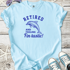 Light blue t-shirt featuring dolphin graphic and 'Retired and Feeling Fin-tastic!' text.