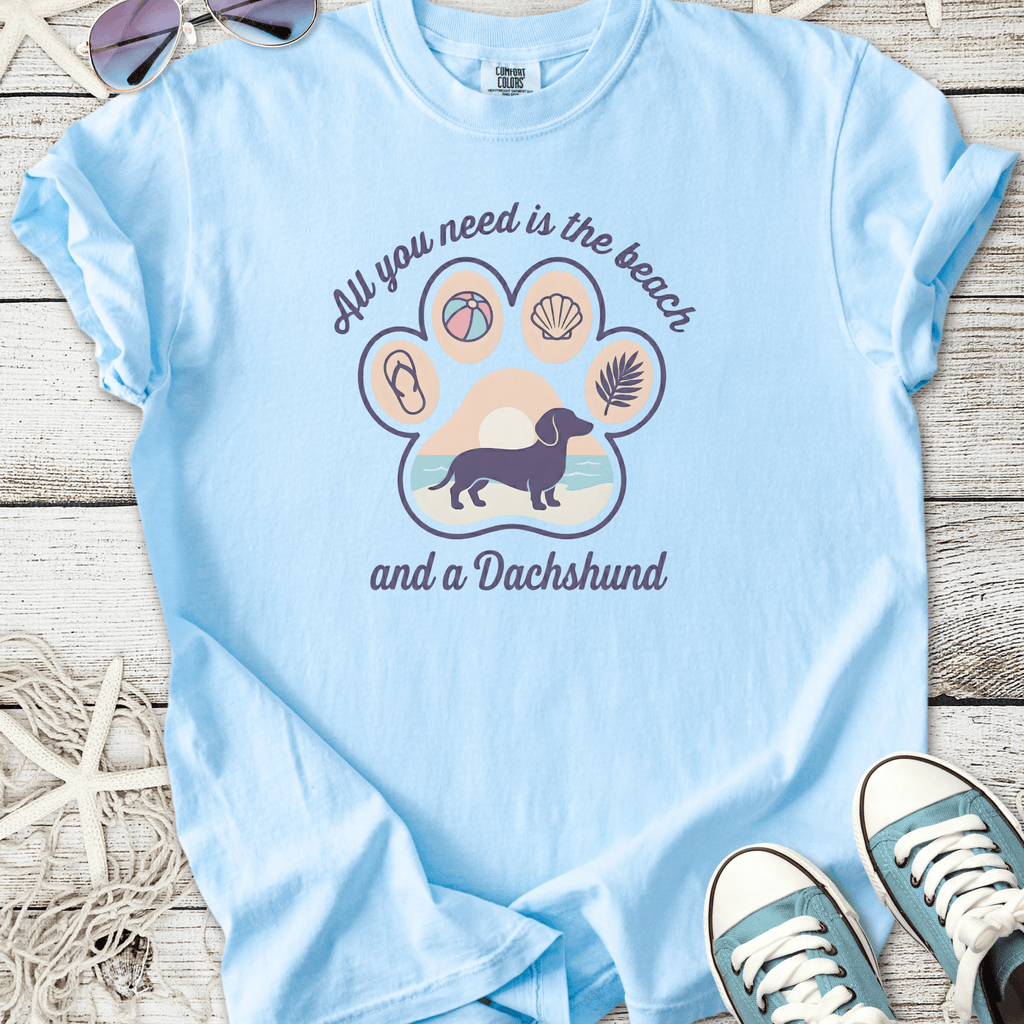 Light blue t-shirt featuring a dachshund graphic and beach-themed design. Perfect for dog lovers.