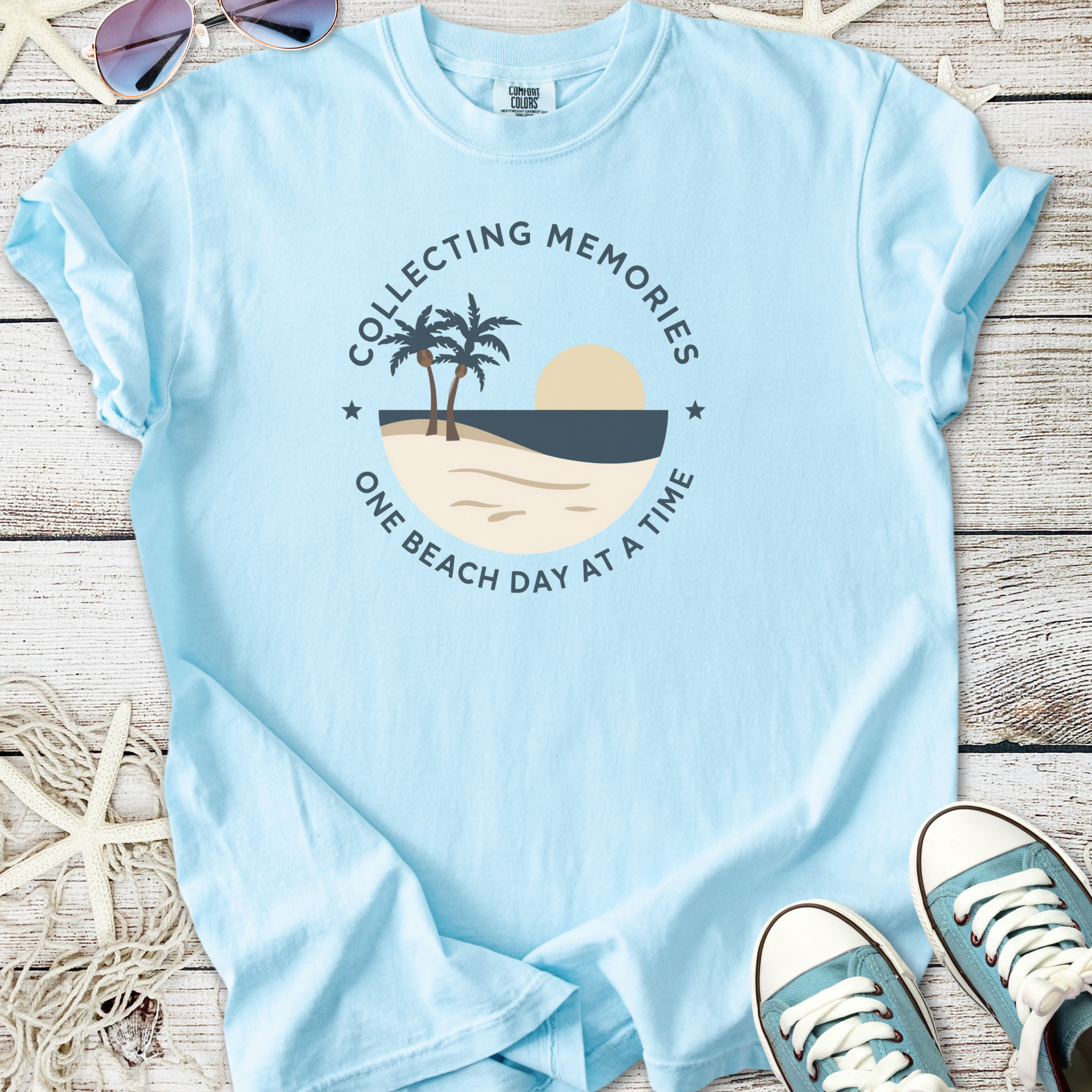 Light blue t-shirt with 'Collecting Memories' beach graphic, perfect for summer outings.