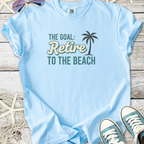 Light blue t-shirt with 'Retire to the Beach' graphic, soft cotton material, perfect for summer wear.