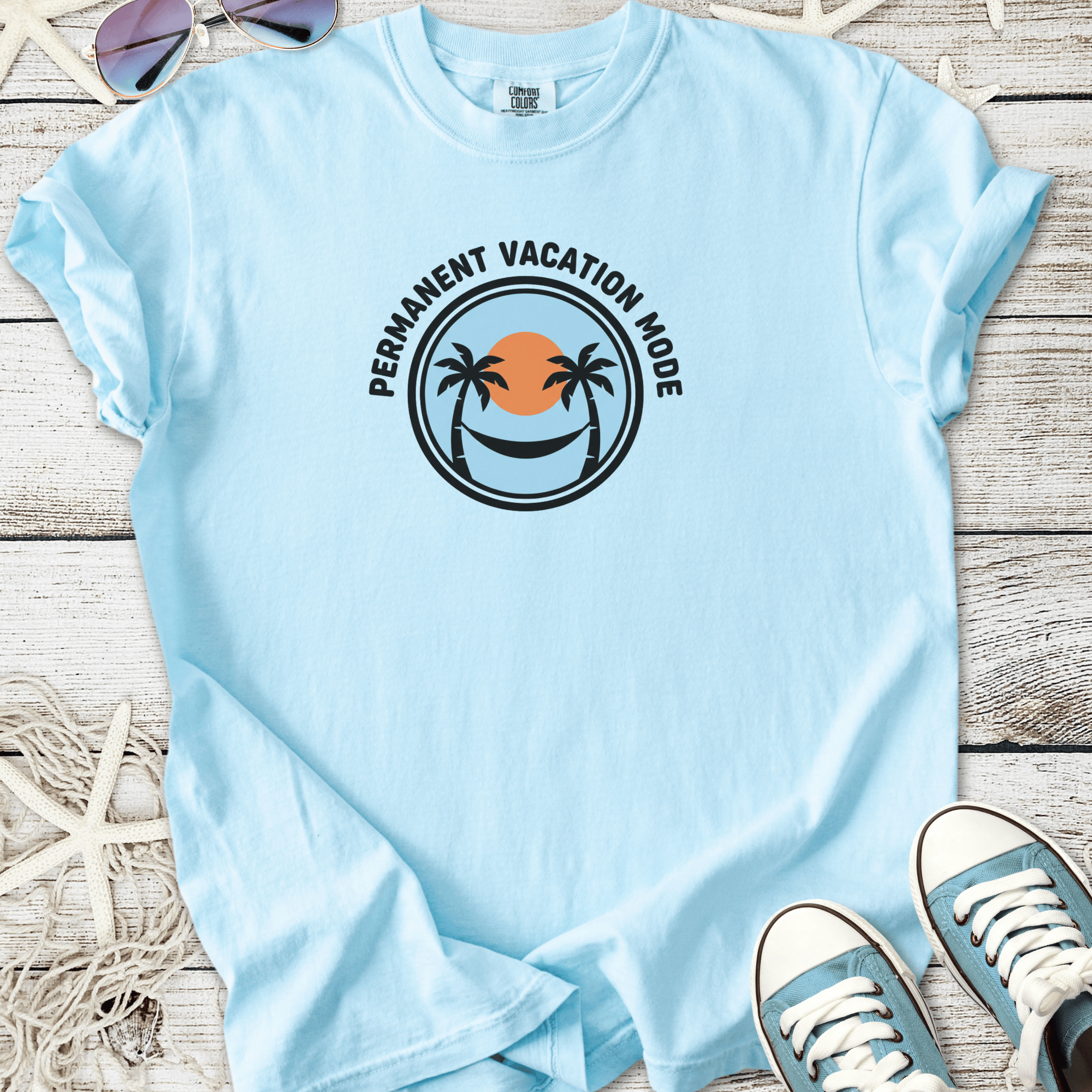 Light blue t-shirt with 'Permanent Vacation Mode' graphic, featuring palm trees and a sunset design.