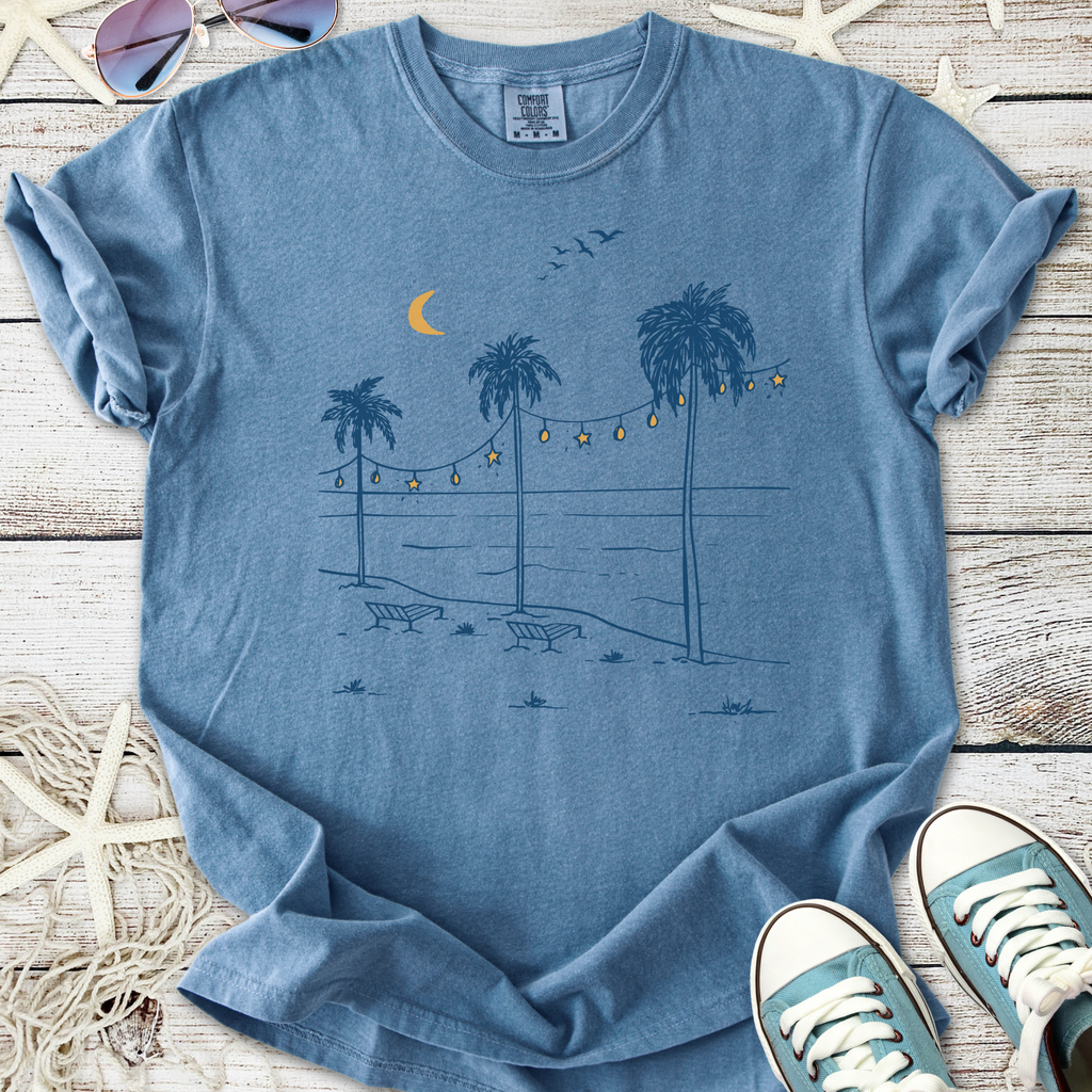 Light blue graphic t-shirt featuring palm trees, beach scene, and string lights for a casual summer vibe.