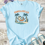 Light blue t-shirt featuring a cartoon dog relaxing in a hammock with palm trees, perfect for casual wear.