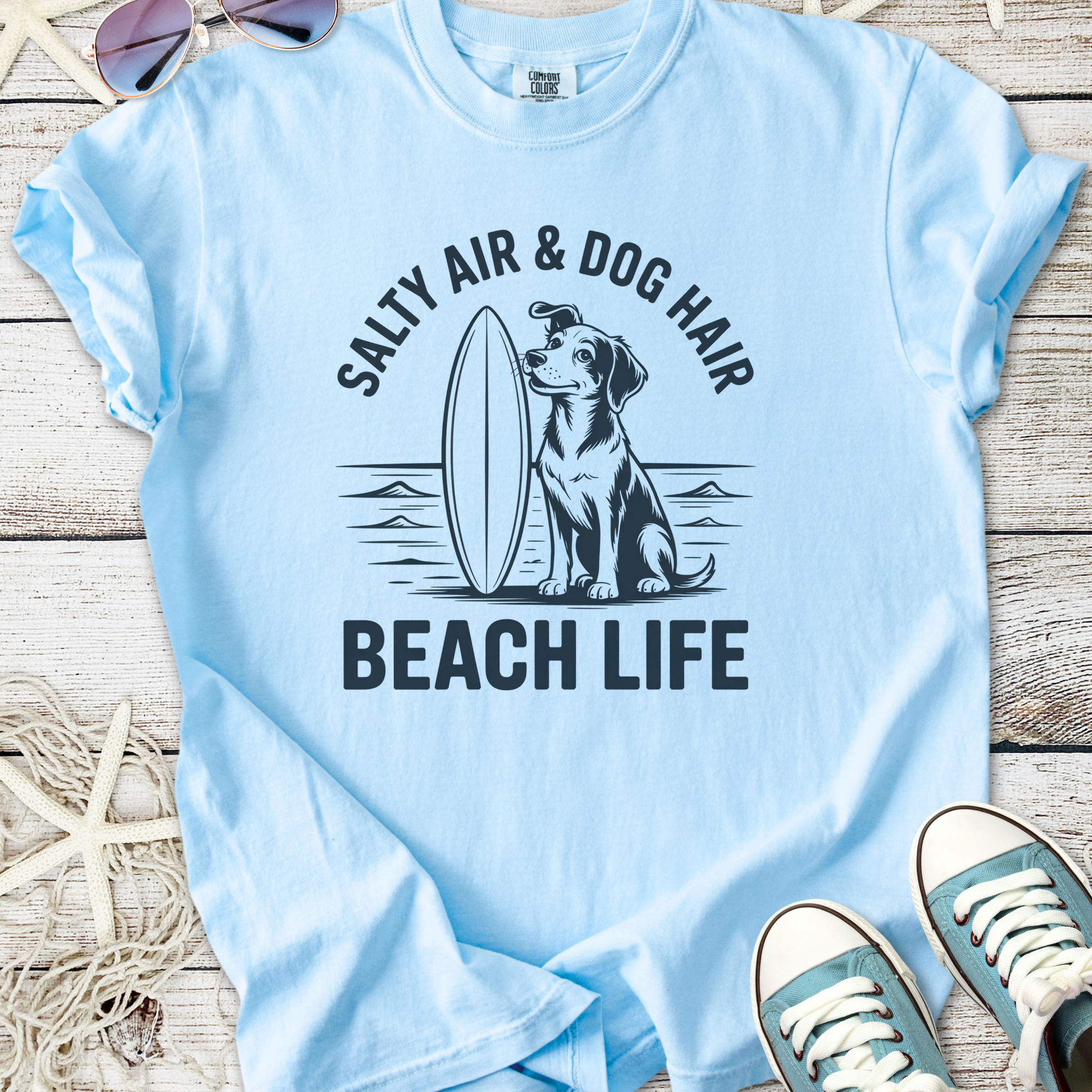 Light blue t-shirt with dog graphic and 'Salty Air & Dog Hair Beach Life' slogan, perfect for beach lovers.