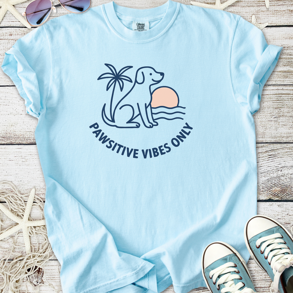 Light blue t-shirt featuring a dog, palm tree, and 'Pawsitive Vibes Only' graphic design.