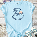 Light blue t-shirt featuring a dog, palm tree, and 'Pawsitive Vibes Only' graphic design.