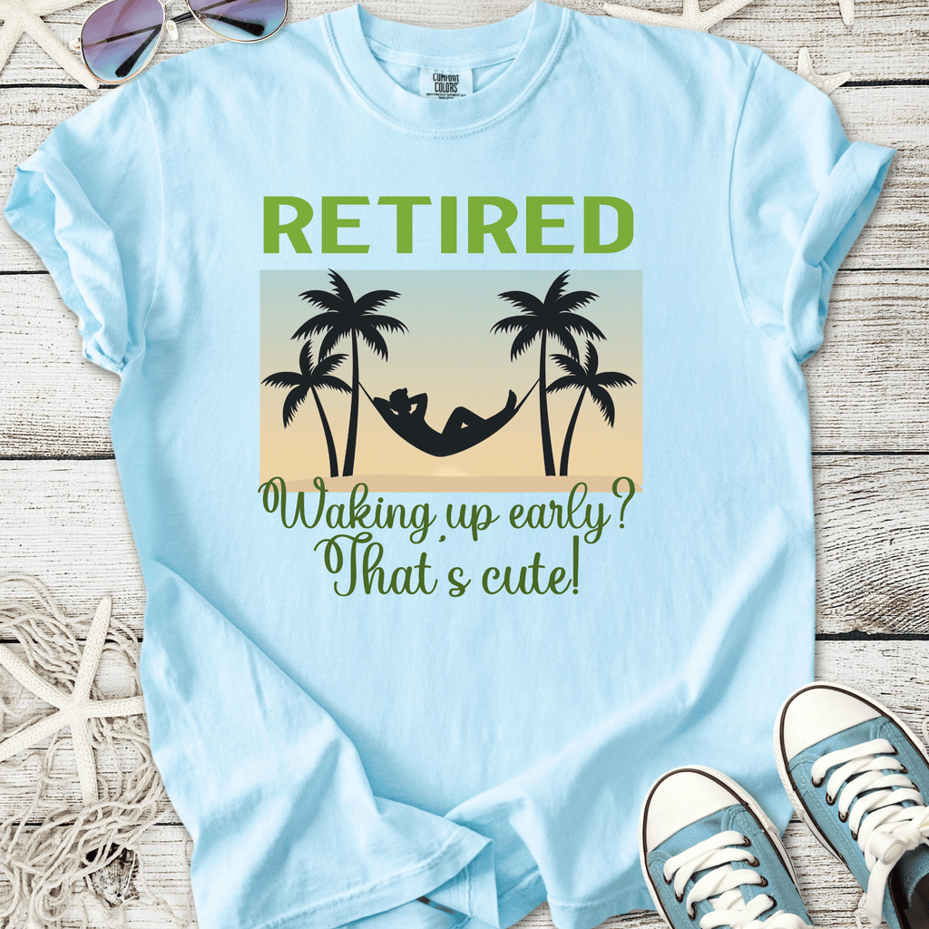 Light blue retired t-shirt with hammock and palm tree design, humorous text about waking up early.