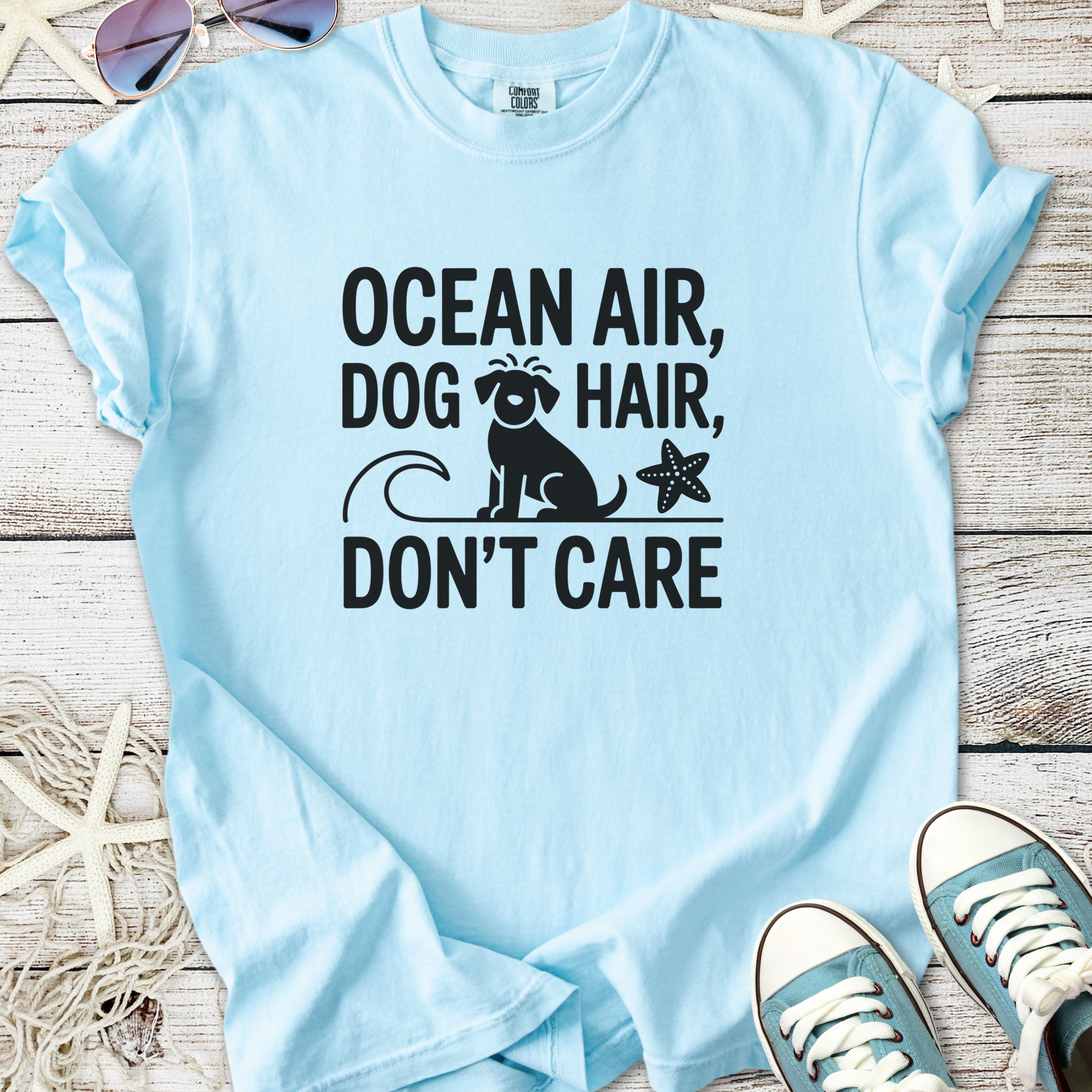 Light blue cotton t-shirt with 'Ocean Air, Dog Hair, Don’t Care' graphic for beach lovers.
