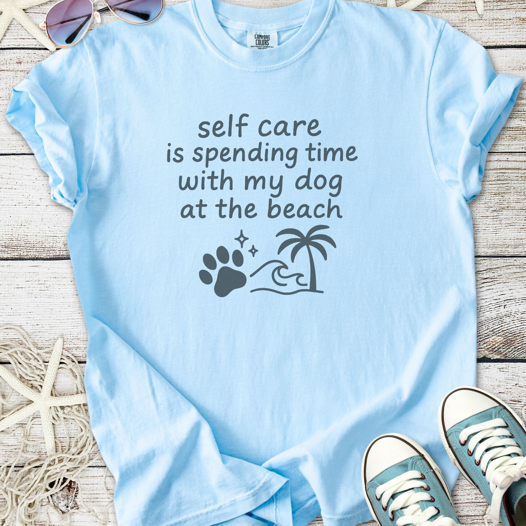 Light blue t-shirt with 'self care is spending time with my dog at the beach' graphic design.