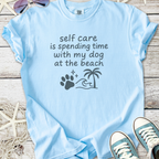 Light blue t-shirt with 'self care is spending time with my dog at the beach' graphic design.