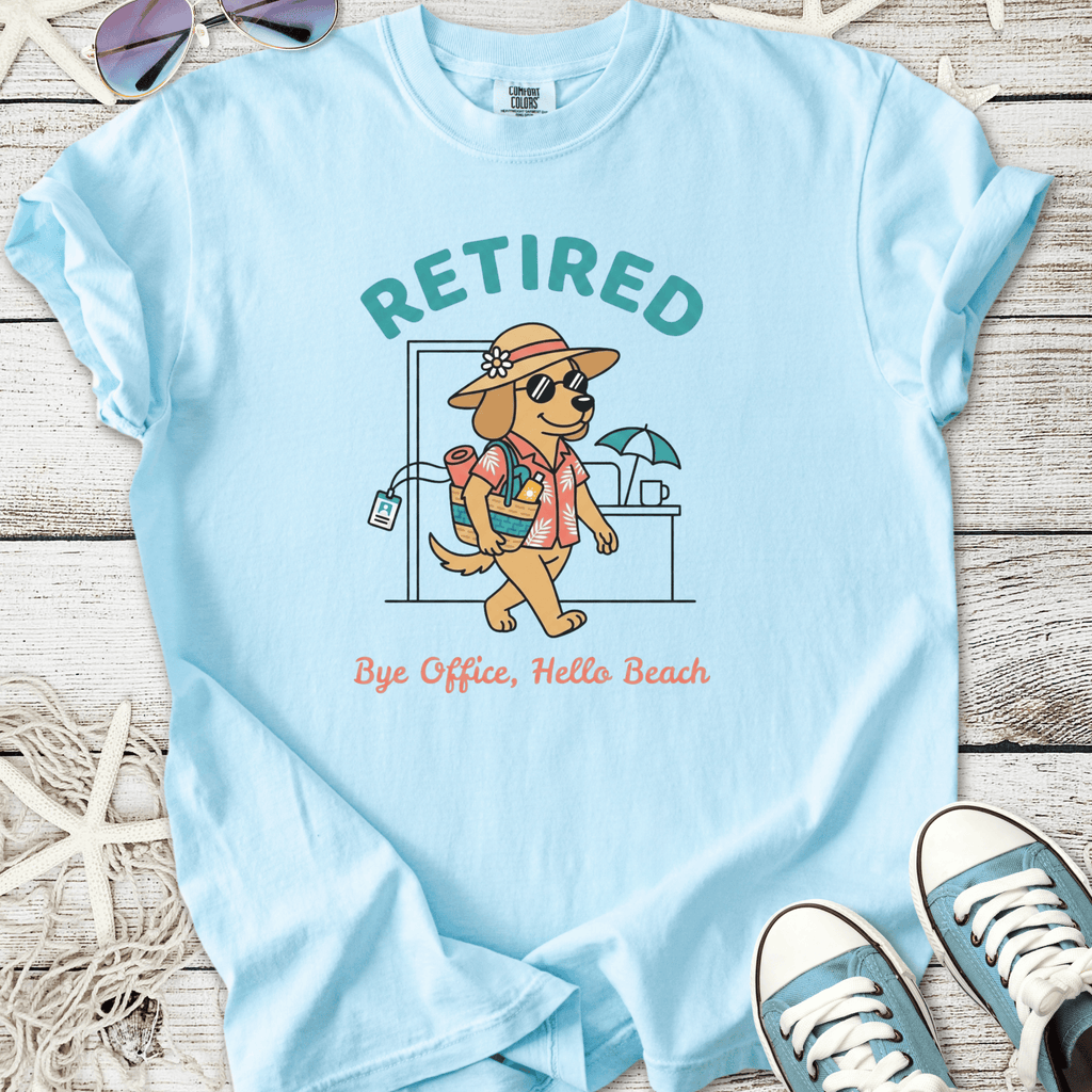 Light blue t-shirt featuring a cartoon dog in sunglasses, promoting a 'Retired' beach lifestyle.