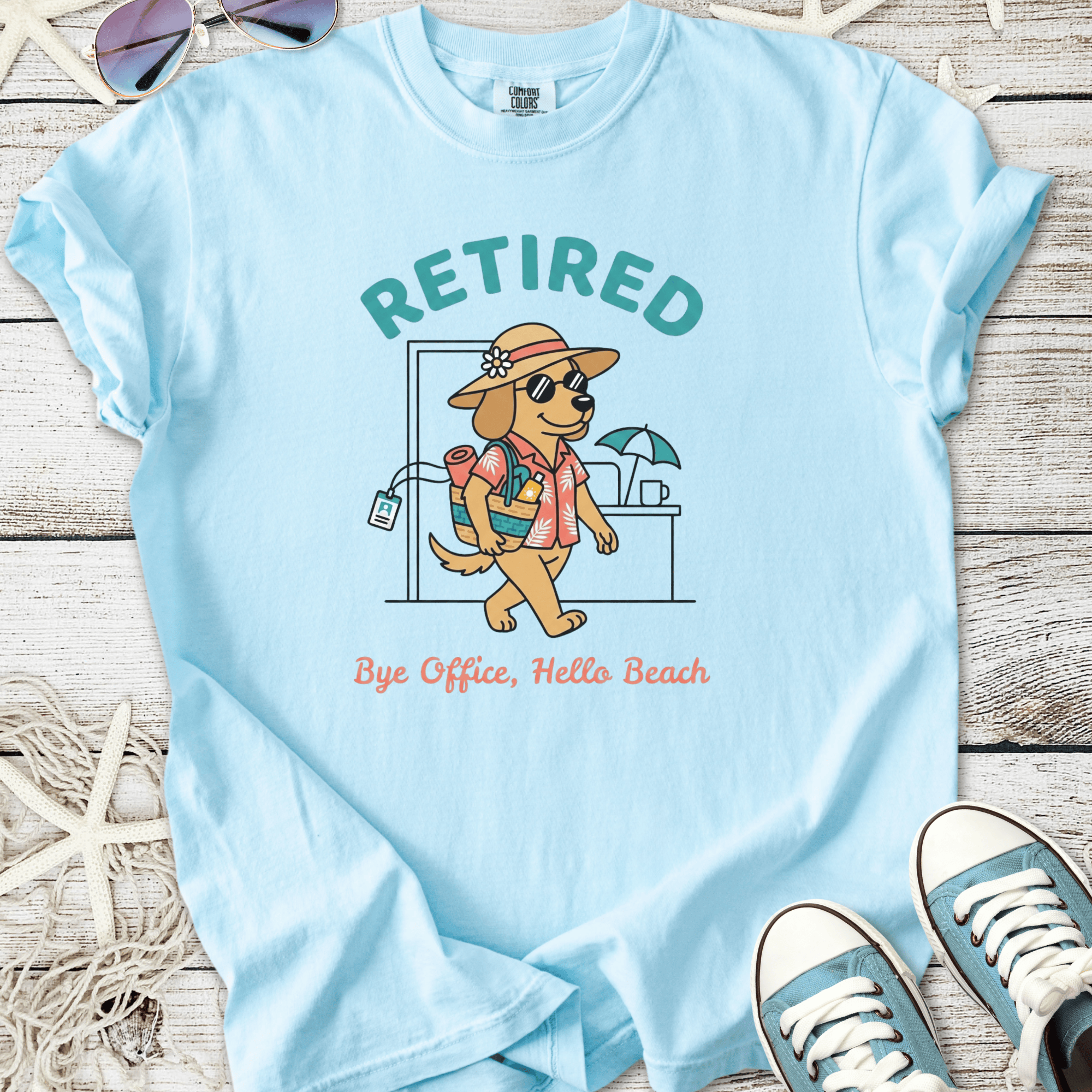 Light blue t-shirt featuring a cartoon dog in sunglasses, promoting a 'Retired' beach lifestyle.