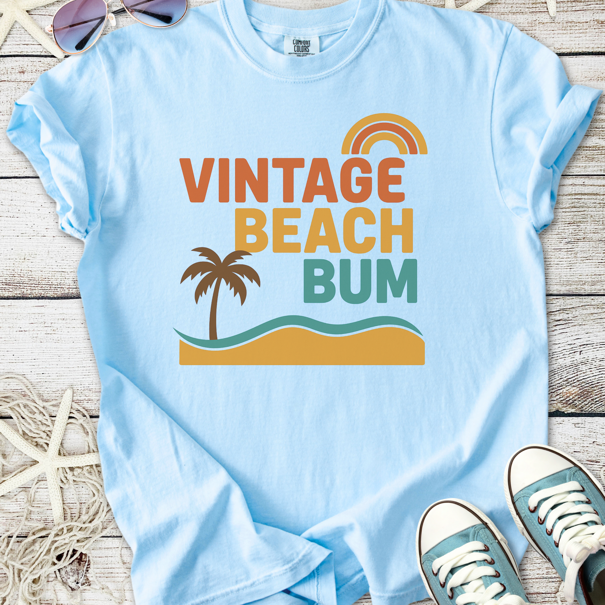 Light blue vintage style t-shirt featuring 'Vintage Beach Bum' design with palm and wave graphics.