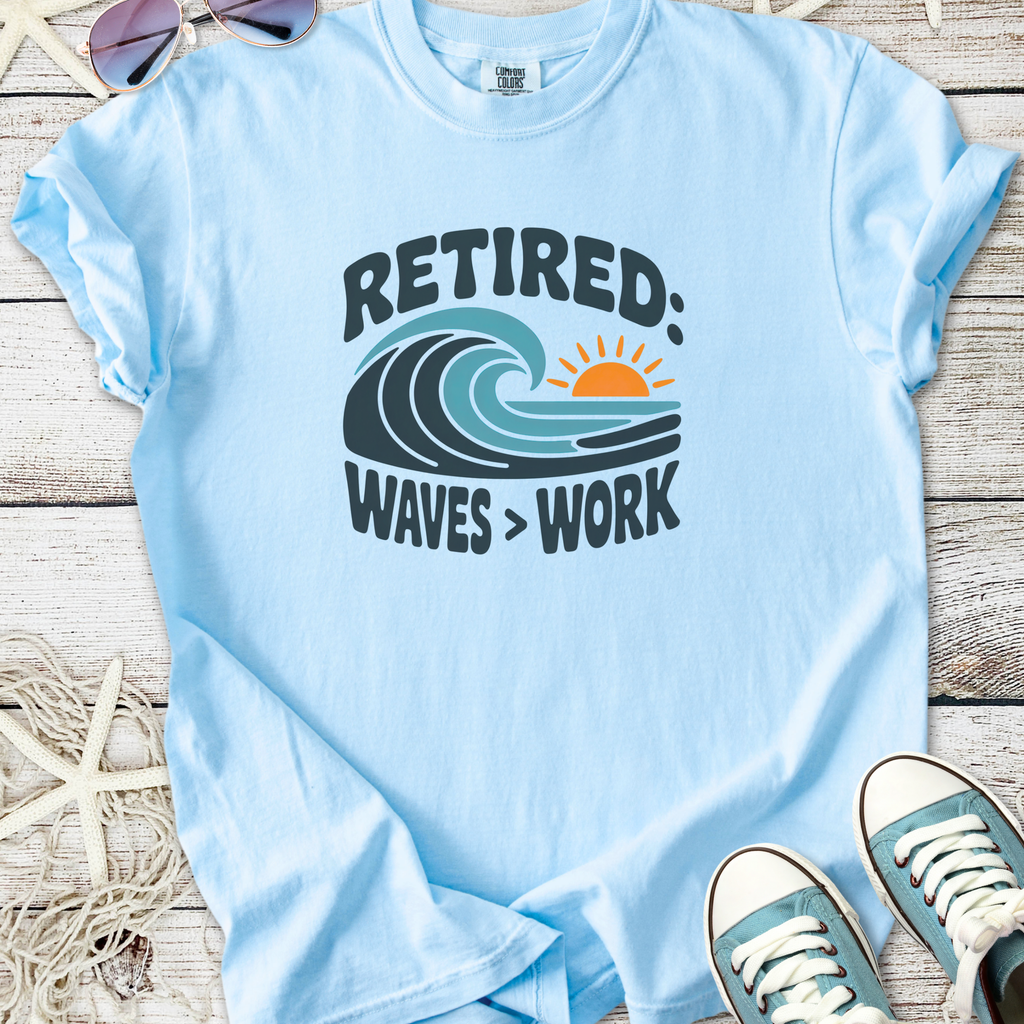 Light blue retired graphic t-shirt featuring waves and sun design, perfect for casual wear.